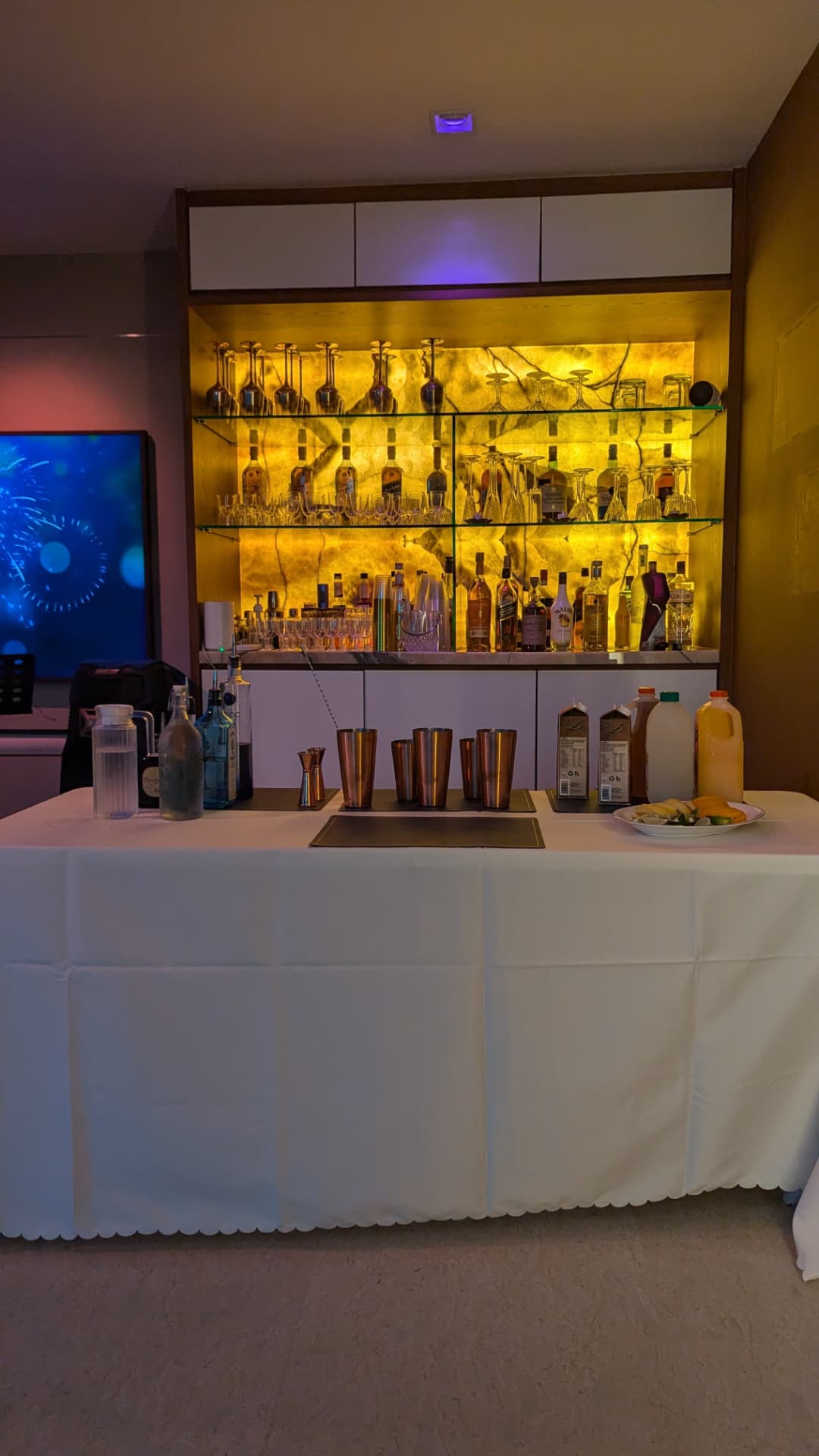 In-home private party bar setup in Singapore with shakers, mixers and a backlit spirits display