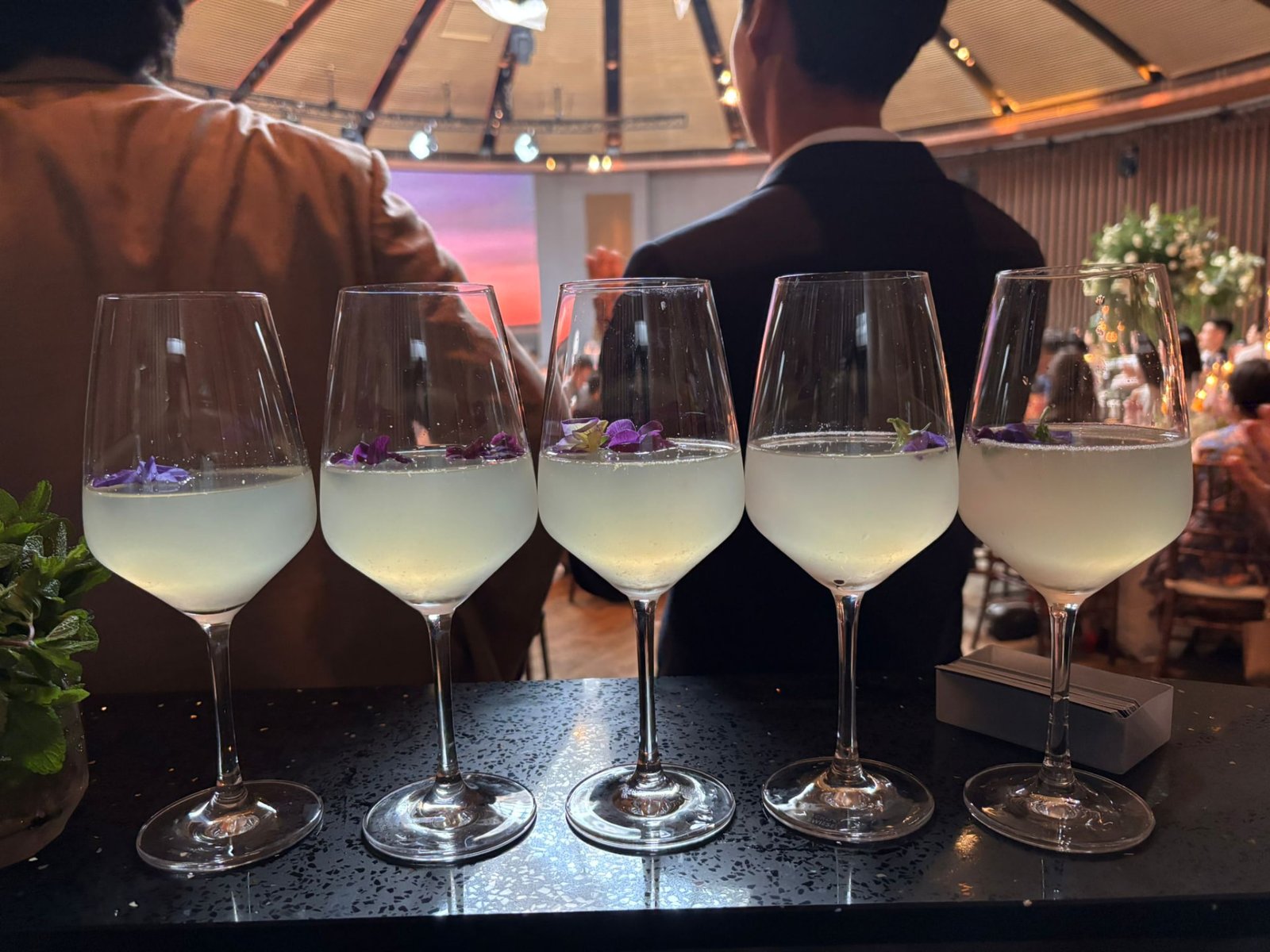 Wedding signature cocktails in wine glasses topped with edible flowers, served in Singapore