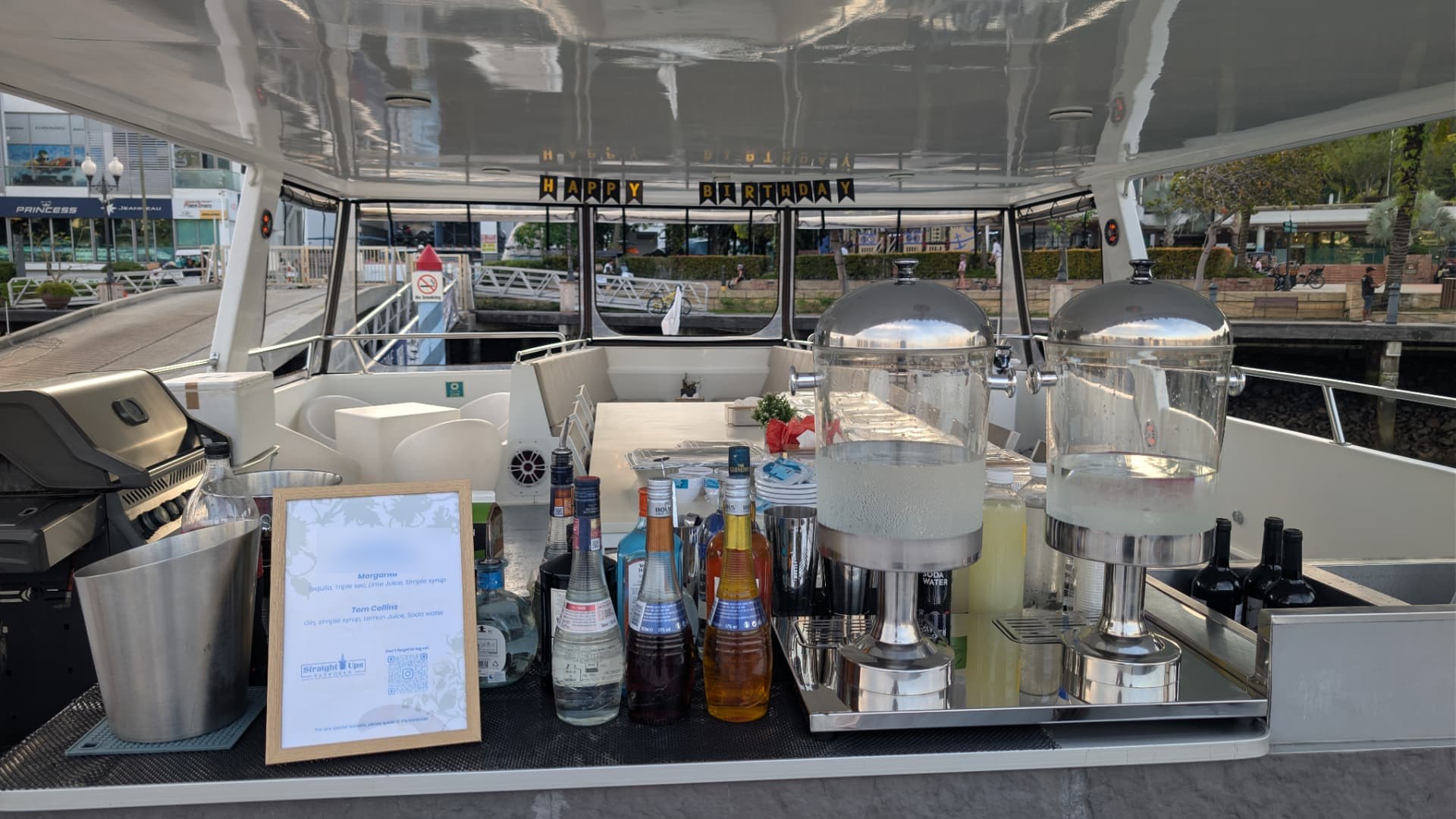 Mobile bar setup on a yacht in Singapore with drink dispensers, spirits and a custom cocktail menu